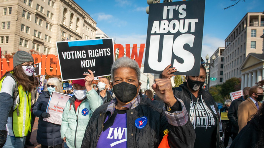 LWVUS president Dr. Turner stands at a march with supporters behind her.