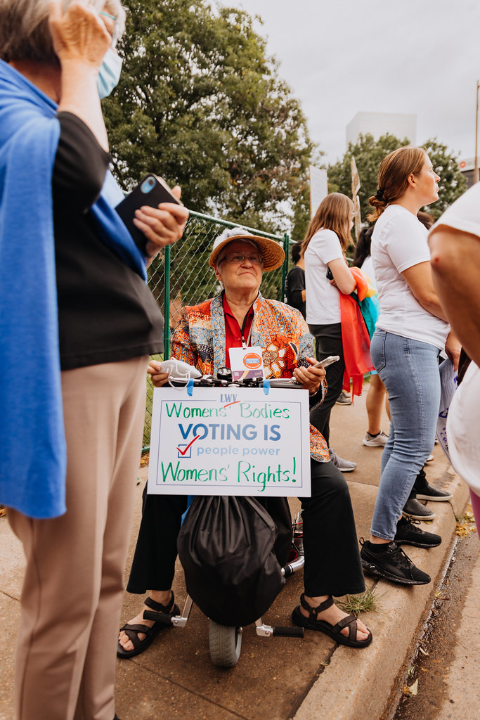 A League member in a wheelchair holding a sign that says "women's bodies, women's rights"