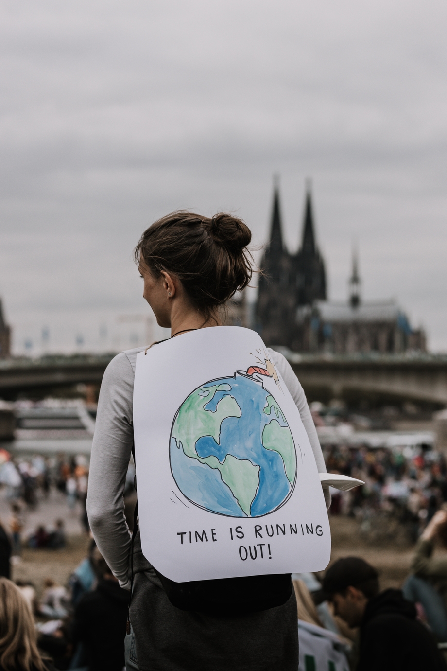 A woman holding a sign over her back with a picture of the Earth